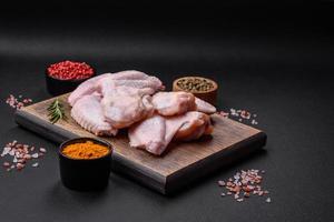 rå kyckling vingar med salt, kryddor och örter på en trä- skärande styrelse foto
