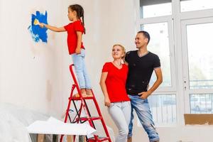 ung familj håller på med målning jobb under Hem renovering foto