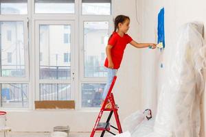förtjusande liten flicka reparation vägg i lägenhet, begrepp av lätt Hem renovera foto