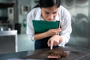 porträtt av studerande matlagning lärling ta anteckningar på varje steg som de kock kockar i de kulinariska akademins kök. foto