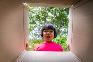 asiatisk barn spelar i kartong lådor foto