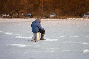 person som fiskar på is med bilar i bakgrunden i Vladivostok, Ryssland foto