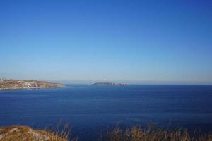 marinmålning av en vattenkropp och kust med en klarblå himmel i Vladivostok, Ryssland foto