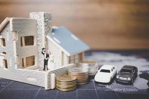 miniatyrbrud och brudgum med mynt framför ett hem, framgångsrikt familjekoncept foto