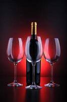 vinflaska och glas med svart bakgrund och rött foto