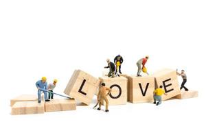 miniatyrarbetare som bygger ordet kärlek på träklossar med vit bakgrund, alla hjärtans dagskoncept foto