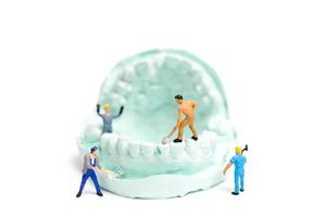 miniatyrarbetare som fyller falska tänder och placerar dem i en protes med gips, tandproteslaboratoriekoncept foto