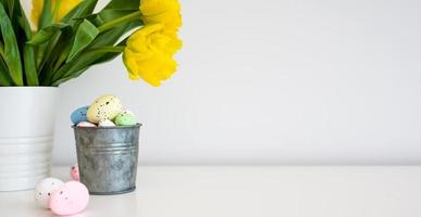 påsk ägg i pastell färger och färsk vår gul tulpaner på en tabell. kopia Plats. hälsning kort med en plats till kopia de text. foto