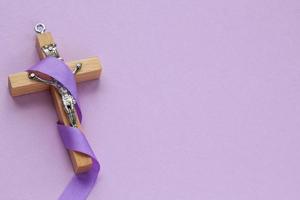 kristen religiös trä- korsa krucifix med violett band på lila bakgrund. katolik religion symbol. Bra fredag, lent säsong, handflatan söndag, aska onsdag och helig vecka begrepp foto