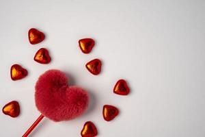 fluffig röd hjärta och massor av skinande godis i de form av hjärtan insvept i folie foto