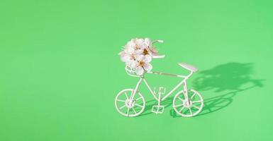 dekorativ cykel med en korg med blommor på en grön bakgrund med kopia utrymme. vårens minimalistiska koncept foto