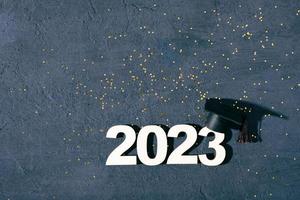 klass av 2023 begrepp. trä- siffra 2023 med graderad keps på mörk bakgrund med glitter foto