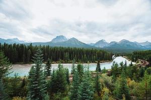 morants kurva, rosett flod flöden genom skog och järnväg Spår. storm berg i de bakgrund. slott klippa synpunkt, rosett dal Parkway, banff nationell parkera, kanadensisk steniga, alberta, Kanada. foto