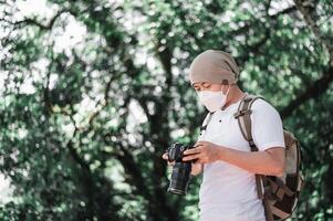 asiatisk resande man kontroll en bild på kamera på de parkera foto