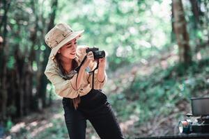 ung kvinna använda sig av kamera tar Foto med Lycklig på läger