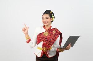 porträtt av skön thai kvinna i traditionell Kläder Framställ med bärbar dator dator foto