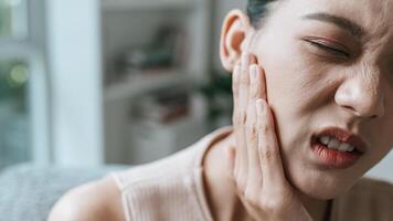 olycklig asiatisk kvinna lidande från smärta i de tand foto