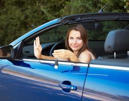leende caucasian kvinna som visar nyckel i en cabriolet foto