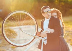 ung eleganta par - de kille med de flicka och cykel utomhus foto