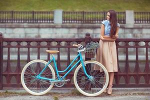 ung skön, elegant klädd kvinna med cykel, sommar och livsstil foto