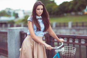 ung vacker, elegant klädd kvinna med cykel foto