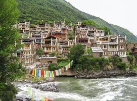 gammal tibetan by korsade förbi en berg flod, resa reportage foto