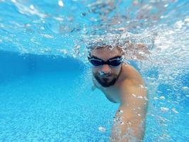 skägg man med glasögon simning under vatten i de slå samman foto