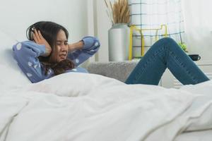 asiatisk kvinna täcker öron med händer som lägger på sängen i sovrummet