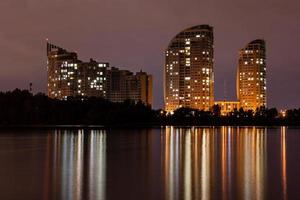 natt stad med reflexion av hus i de flod foto