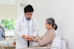 asiatisk manlig läkare förklara medicin till äldre kvinna patient i sjukhus. foto