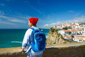 kvinna med en ryggsäck åtnjuter en se av de hav kust nära azenhas do mar, portugal foto