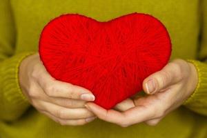 närbild på röd hjärta tillverkad från ull i hand av kvinna foto