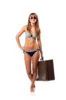 full längd porträtt av en skön ung kvinna Framställ i en bikini och solglasögon med en resväska i hand på vit foto