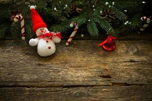 jul träd grenar med jul dekorationer och snögubbe på trä- textur foto