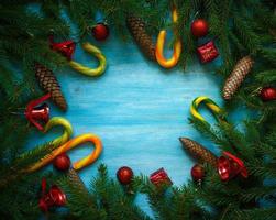 jul gräns med gran träd grenar, kottar, jul dekorationer och godis sockerrör på blå trä- styrelser foto