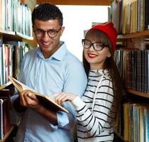 ung studerande par välja böcker i de bibliotek foto