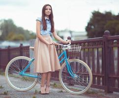 ung vacker, elegant klädd kvinna med cykel foto