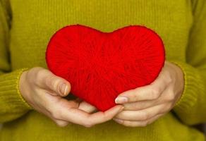 närbild på röd hjärta tillverkad från ull i hand av kvinna foto
