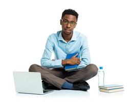 afrikansk amerikan högskola studerande med bärbar dator, böcker och flaska av vatten Sammanträde på vit foto