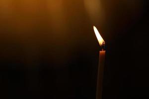 ett ljus flamma ljus på natt med bokeh på mörk bakgrund foto