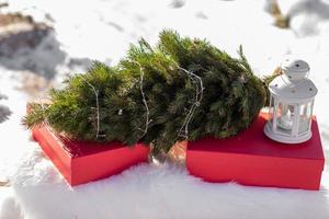 röd gåva lådor, jul träd med krans, vit lykta på vit fluffig pläd utomhus i vinter- snöig dag. festlig bakgrund. högtider, presenterar, ny år och firande begrepp. kopia Plats. foto