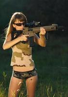flicka med en pistol för fälla skytte och skytte glasögon siktar på en mål foto