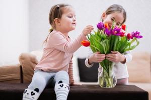 två systrar med vår tulpan bukett. Semester dekor med blommor färgrik tulpaner. foto