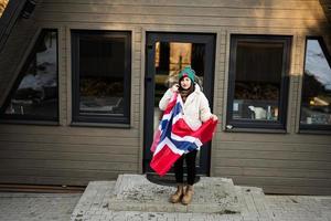 porträtt av kvinna utanför stuga hus innehav Norge flagga. scandinavian kultur, norska människor. foto
