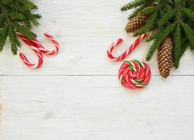 jul gräns med gran träd grenar med koner och godis sockerrör på vit trä- styrelser redo foto
