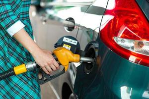 kvinna fyllningar bensin in i henne bil på en gas station foto