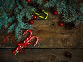 jul gräns med tall träd grenar, kottar, jul dekorationer och godis sockerrör foto