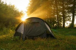turist tält på flodbank på soluppgång foto