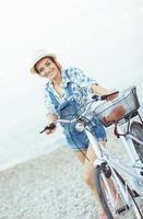 Lycklig kvinna med cykel på de strand foto