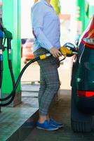 kvinna fyllningar bensin in i de bil på en gas station foto